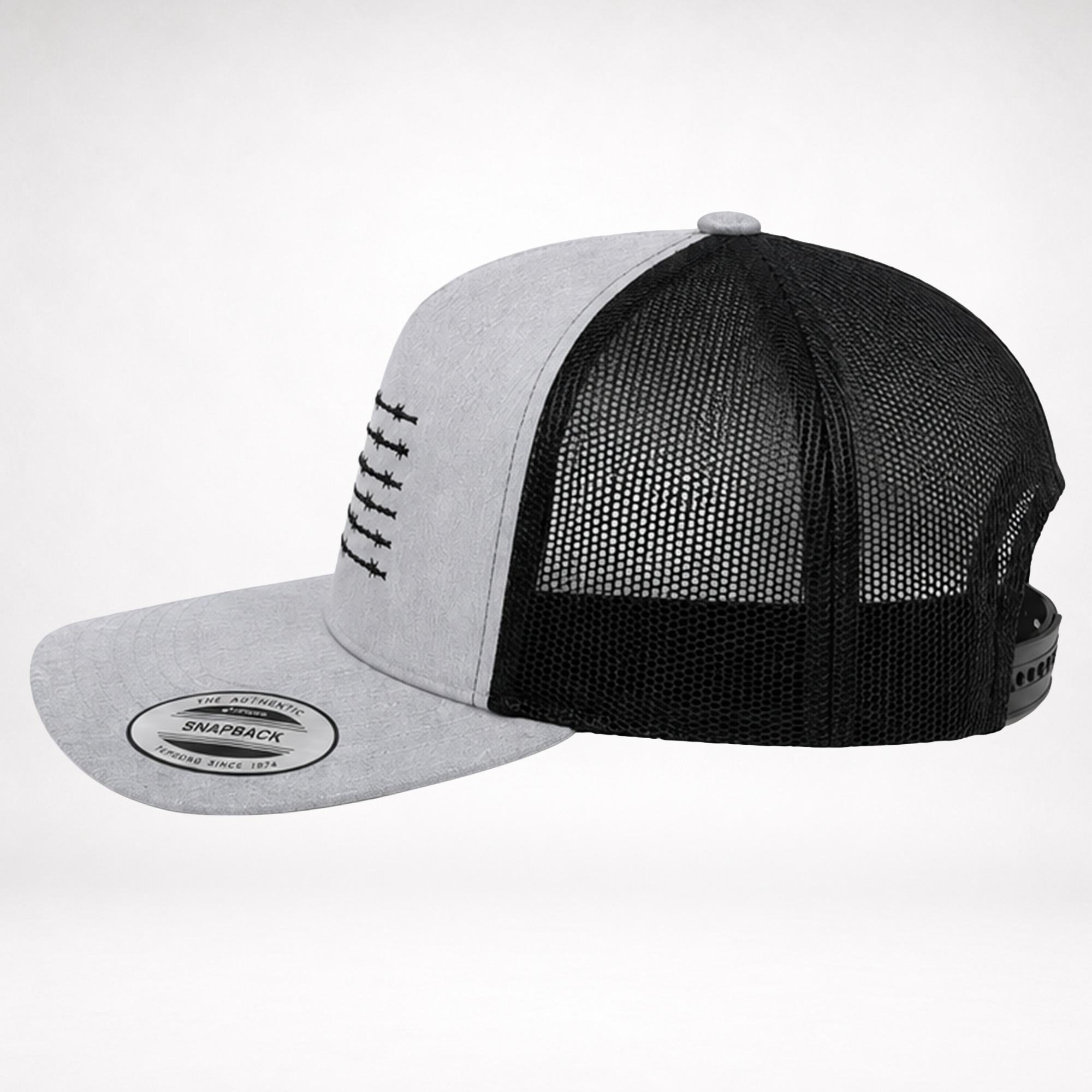 side profile of barbed wire american flag trucker hat with heather gray front, black mesh back, and curved bill
