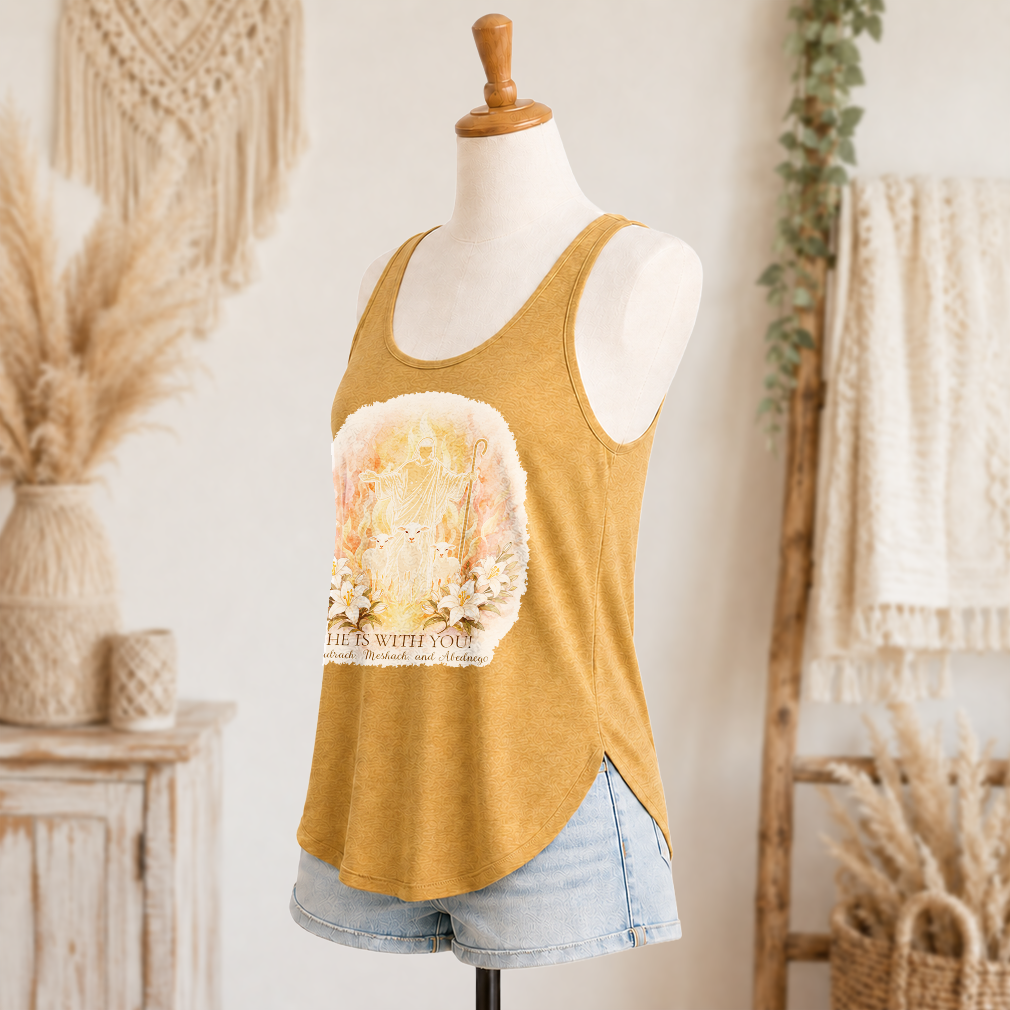 He is with You women’s festival tank side view in antique gold with front Christian artwork and denim shorts