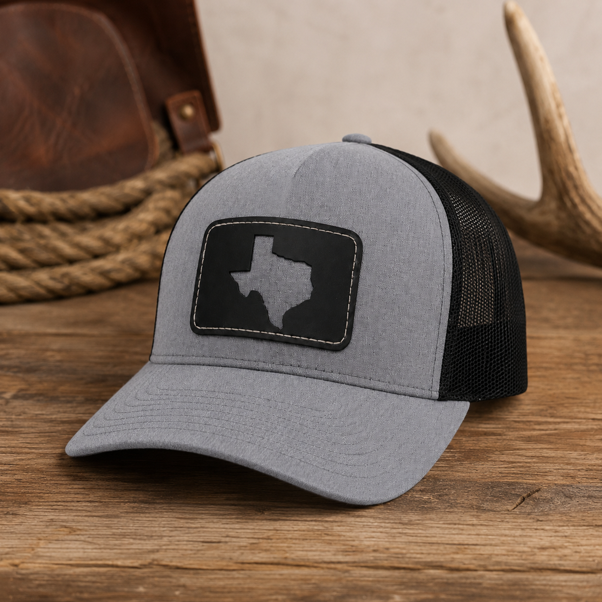 Texas Cutout Patch Trucker Hat displayed on a rustic wood surface with western props in the background