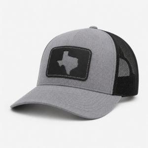 Front side angle of the Texas Cutout Patch Trucker Hat with gray bill, black mesh back, and black Texas cutout patch